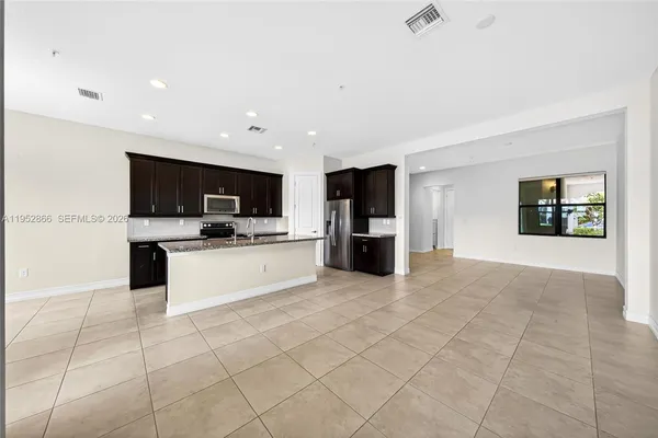 a kitchen with stainless steel appliances kitchen island granite countertop a refrigerator and a sink