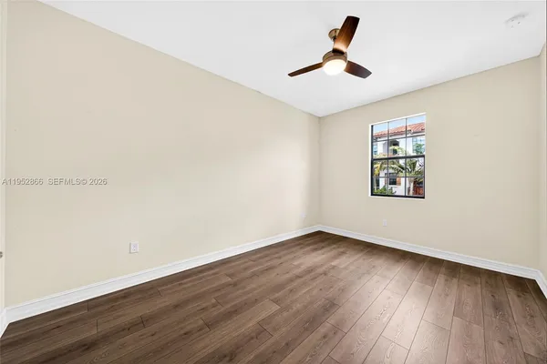 an empty room with wooden floor and ceiling fan