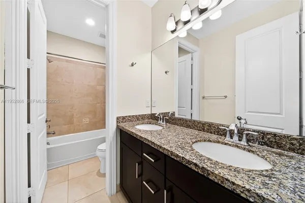 a bathroom with a granite countertop double vanity sink a mirror and a bathtub