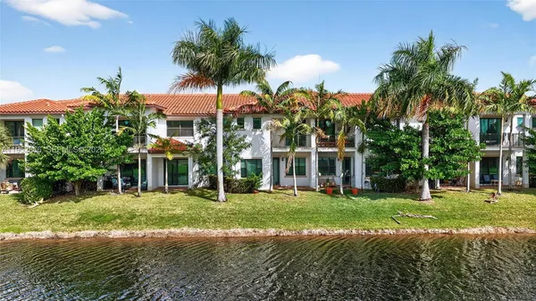 a view of a white house with a big yard and palm trees