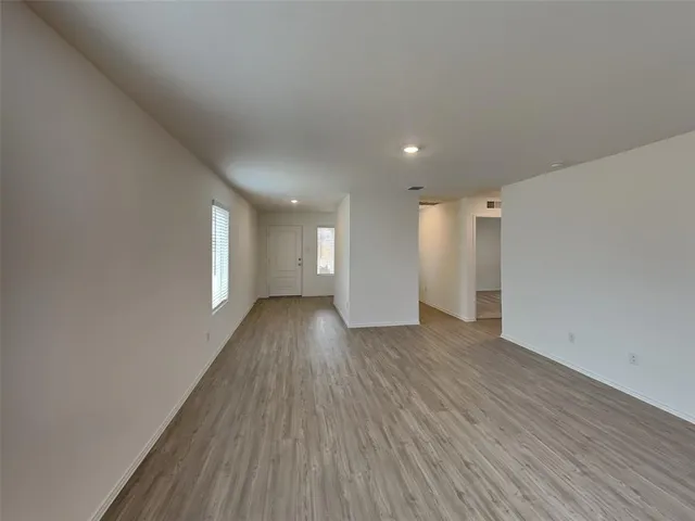 a view of an empty room with wooden floor and windows