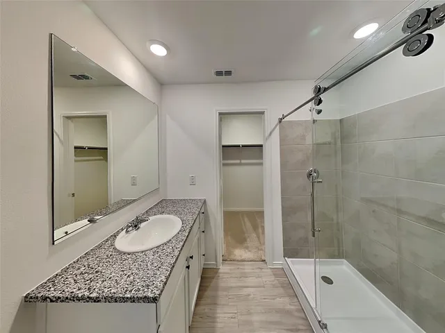 a bathroom with a granite countertop sink shower and mirror