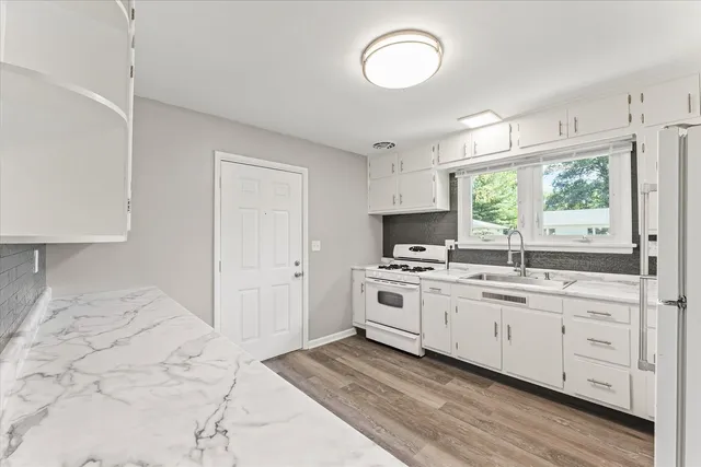 a kitchen with granite countertop a sink a window stainless steel appliances and white cabinets