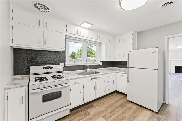 a kitchen with white cabinets white appliances and sink