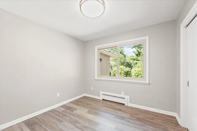 an empty room with wooden floor and windows
