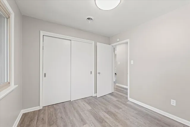 a view of an empty room with wooden floor and windows
