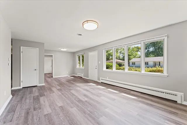 a view of an empty room with wooden floor and a window