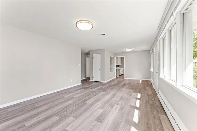 a view of an empty room with wooden floor and a window