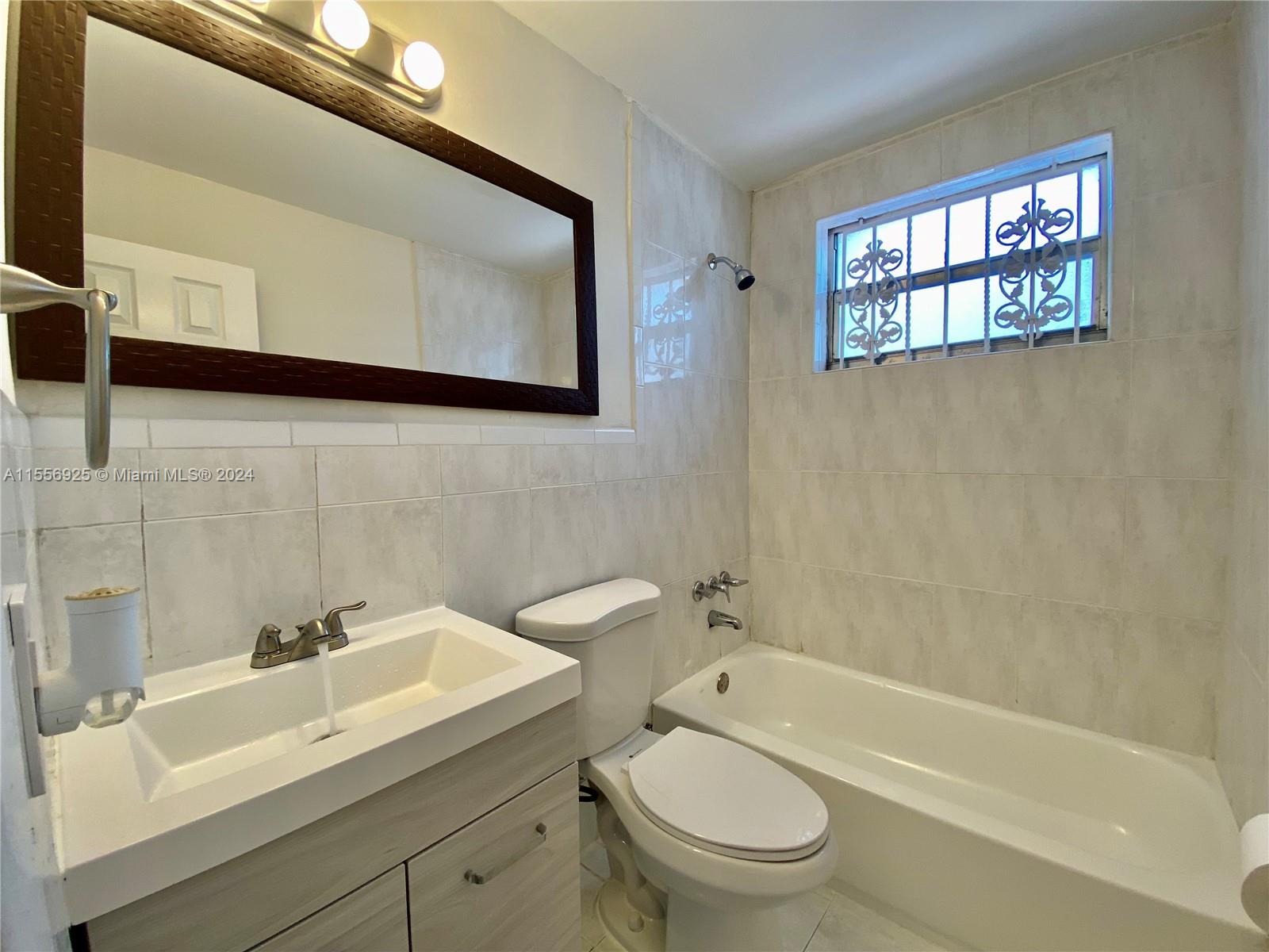 7625 Harding Avenue, Unit 1 Miami Beach, FL 33141 - Photo 6 of 11 a bathroom with a sink toilet a mirror and bathtub
