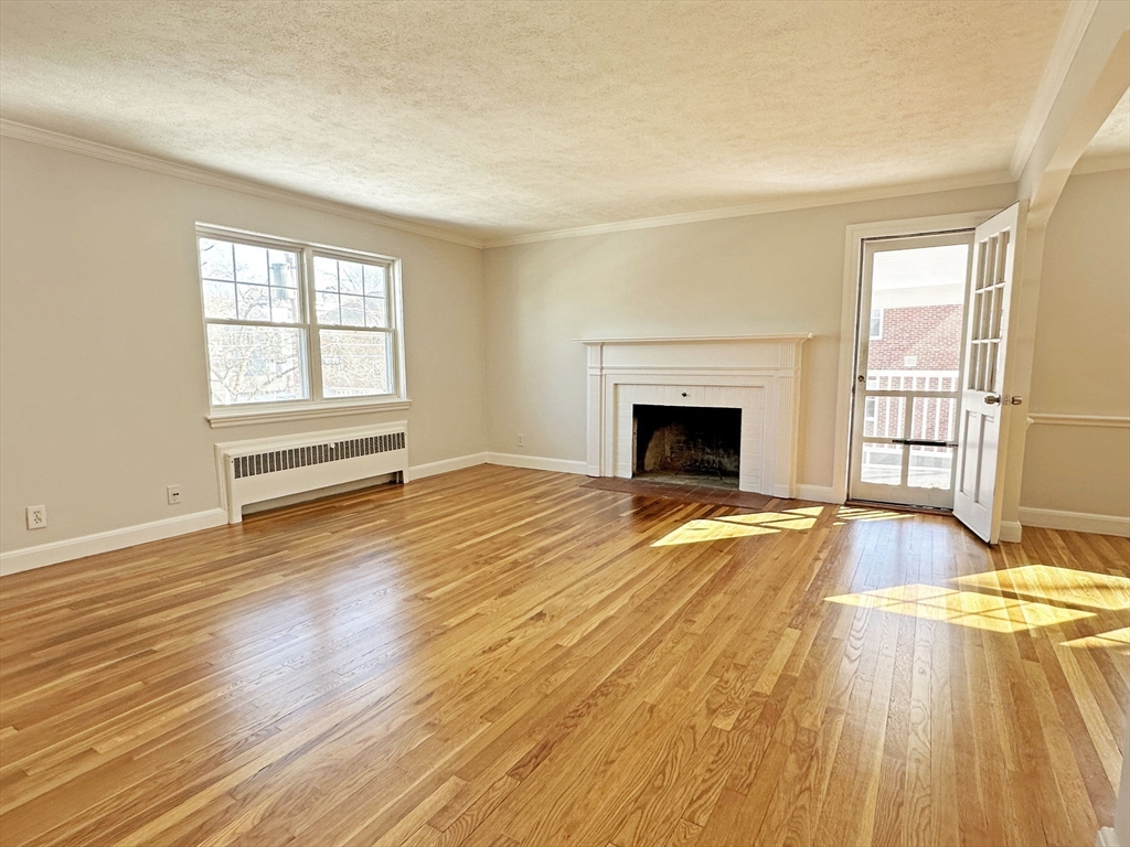 99 Withington Road Newton, MA 02460 - Photo 3 of 33 an empty room with wooden floor fireplace and windows