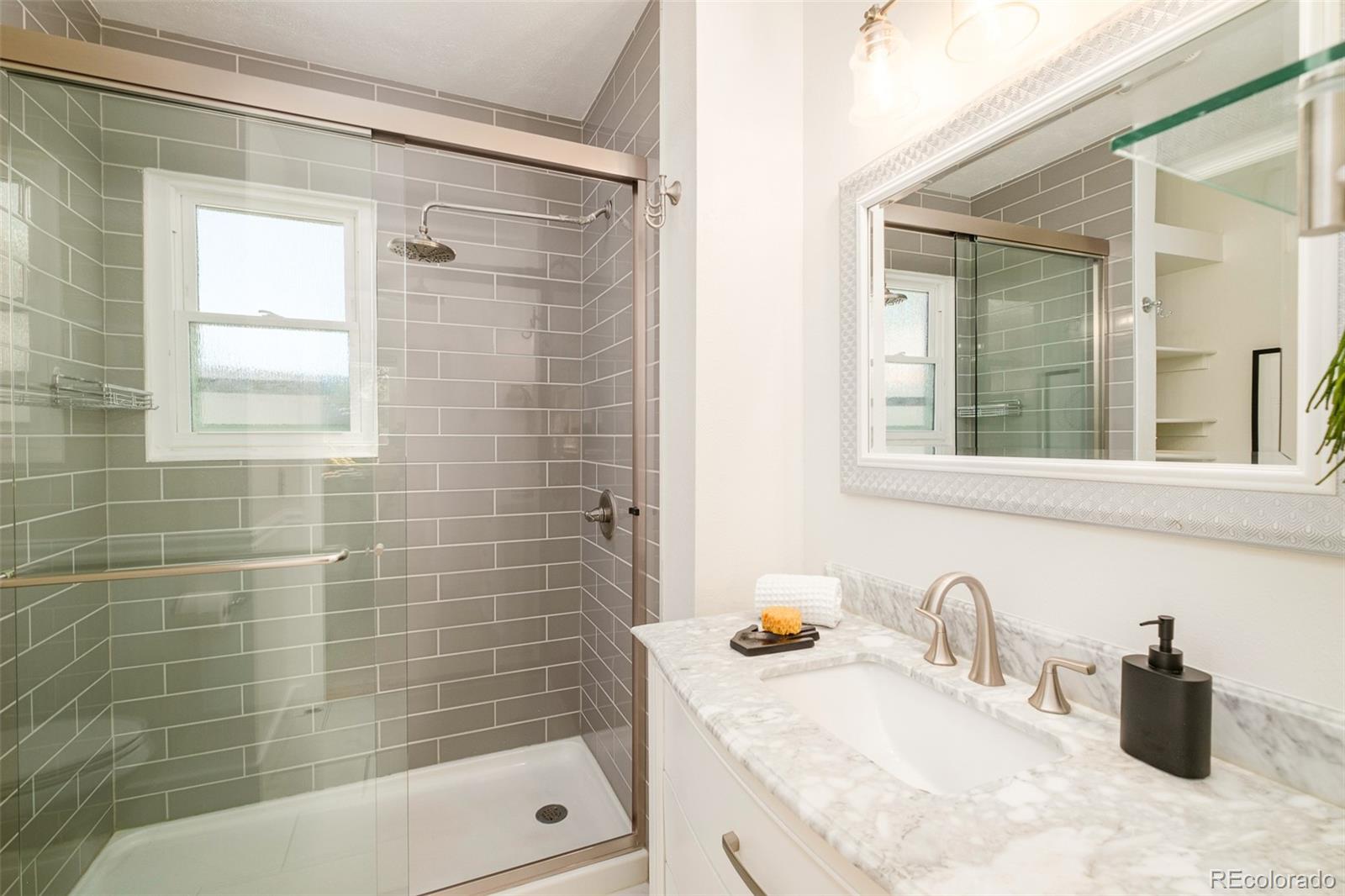 4635 Elm Court Denver, CO 80211 - Photo 15 of 28 a bathroom with a granite countertop sink a mirror a bathtub and shower