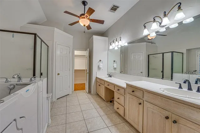 a spacious en suite bathroom with a double vanity sink a large mirror and a shower