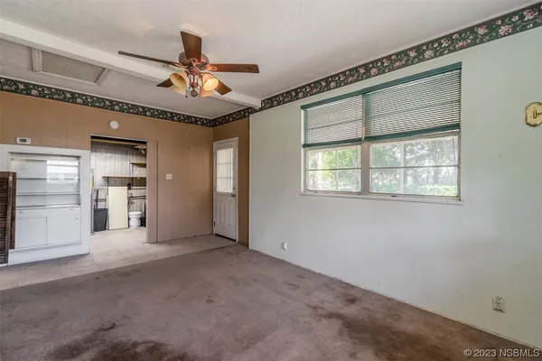 an empty room with windows and fan