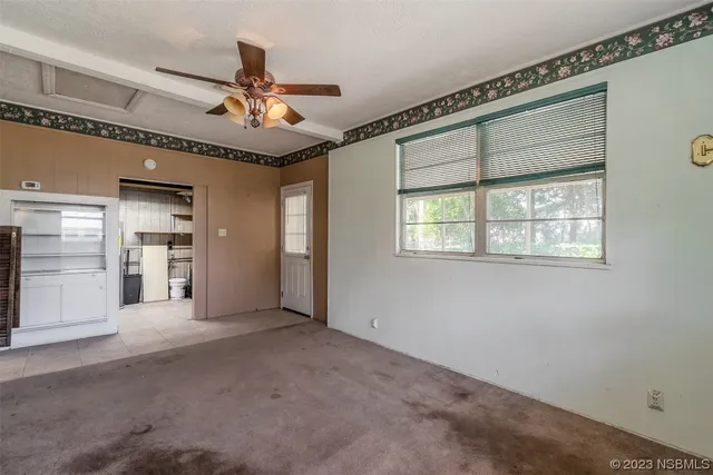an empty room with windows and fan