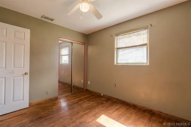a view of empty room with wooden floor and ceiling fan