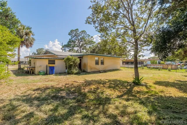a view of a small house with a small yard and large tree