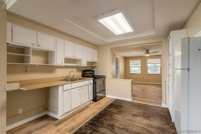 a kitchen with granite countertop a stove a sink and white cabinets