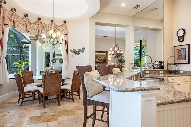a dining room with granite countertop a table chairs and white kitchen view