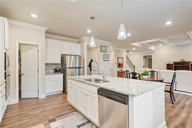 a large kitchen with kitchen island a sink a stove a dining table and chairs with wooden floor