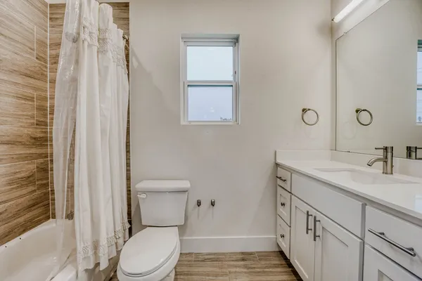 a bathroom with a granite countertop toilet a sink and a mirror