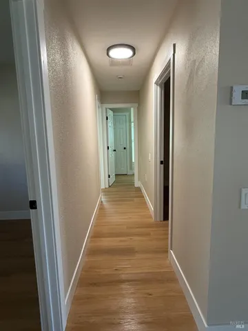 a view of a hallway with wooden floor and a bathroom