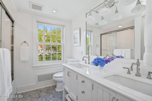 a bathroom with a double vanity sink toilet and a mirror