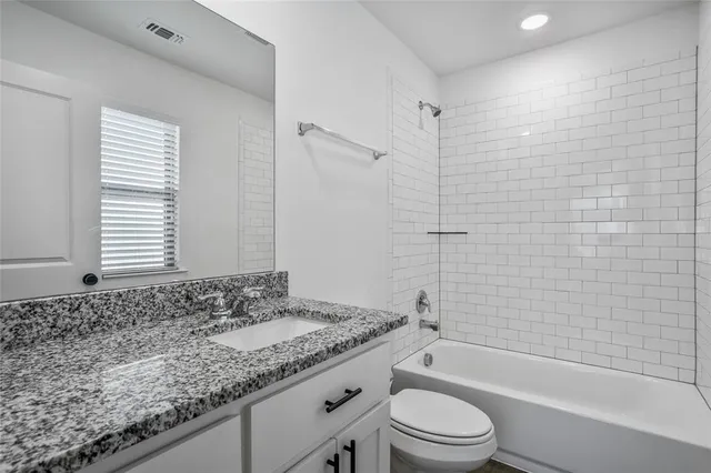 a bathroom with a granite countertop toilet a sink and a bathtub