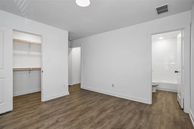 a view of an empty room with wooden floor and closet