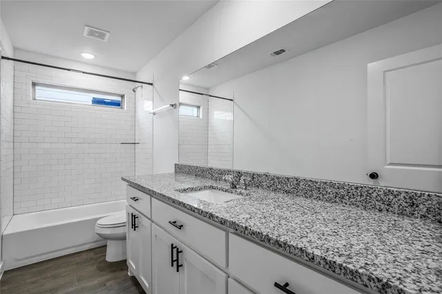 a bathroom with a granite countertop sink a toilet and shower