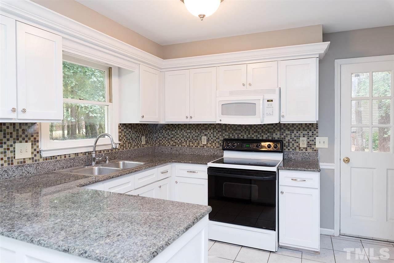 4216 Labrador Drive Raleigh, NC 27616 - Photo 7 of 20 a kitchen with stainless steel appliances granite countertop a stove a sink and white cabinets