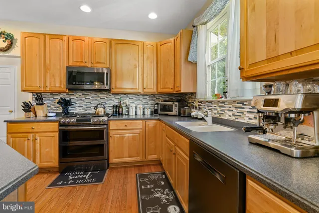 a kitchen with stainless steel appliances granite countertop a stove a sink and a microwave