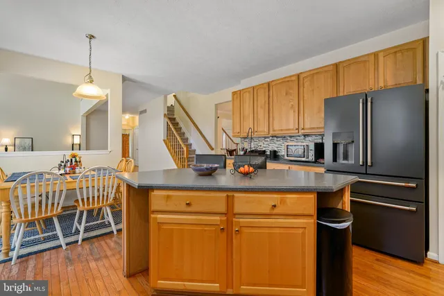 a kitchen with stainless steel appliances granite countertop a refrigerator a stove a sink dishwasher with a dining table and chairs with wooden floor