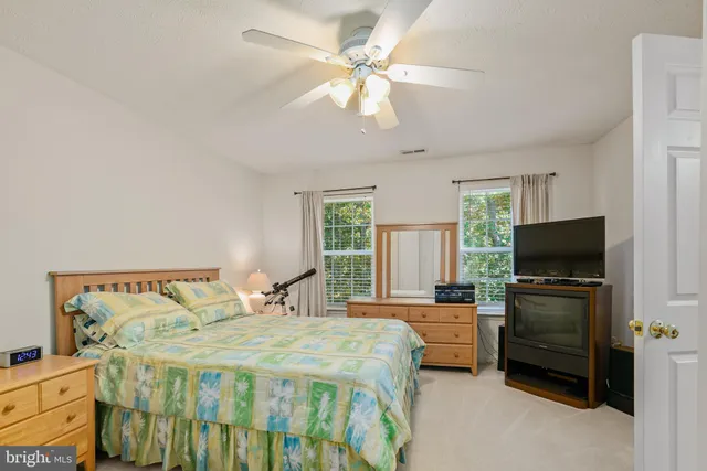 a bedroom with a bed and a flat tv screen on the dresser