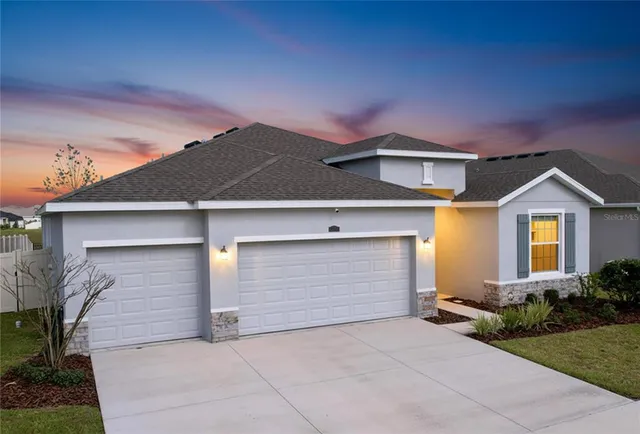 a front view of house with yard and trees in the background