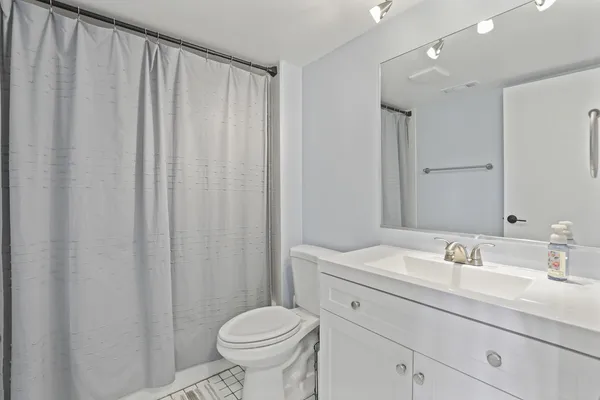 a bathroom with a sink a toilet a mirror and shower curtain