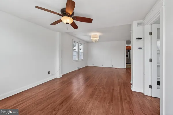 an empty room with wooden floor chandelier fan and windows