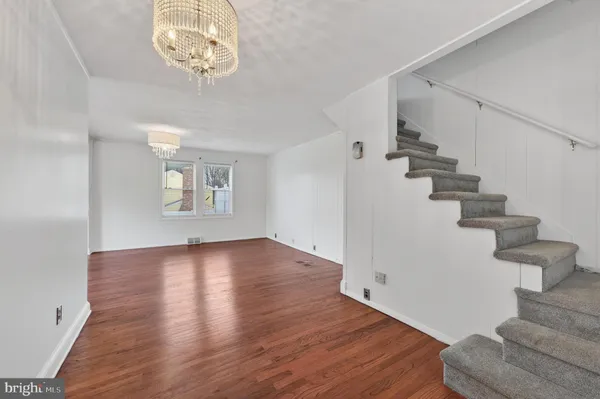 a view of an empty room with wooden floor and a chandelier