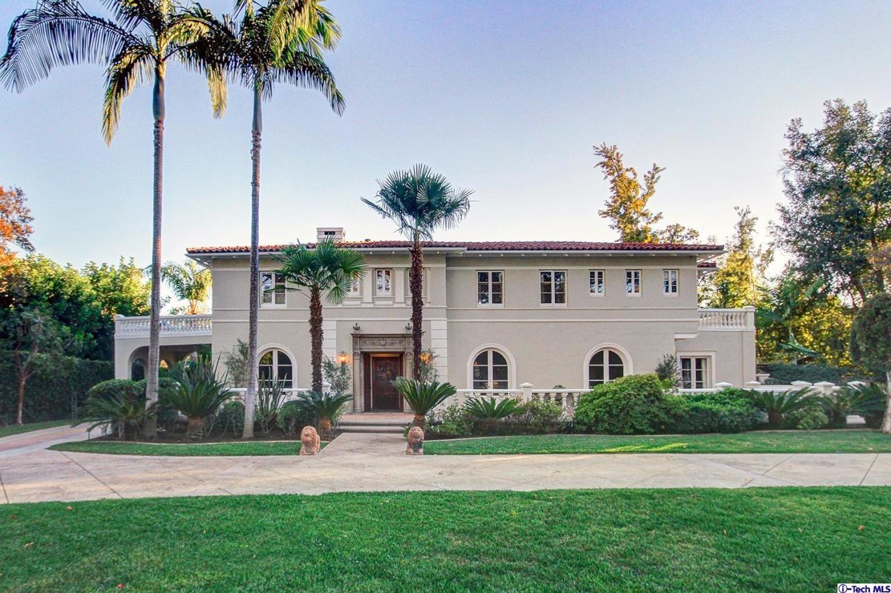 a view of a white house with a big yard and palm trees