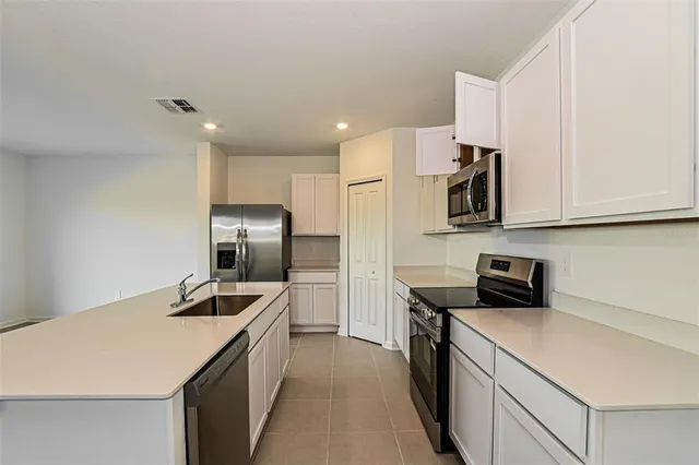 a kitchen with a sink a counter top space stainless steel appliances and cabinets