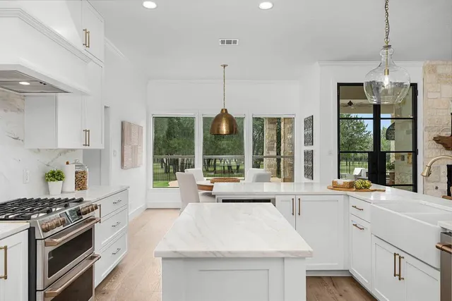 a large white kitchen with a stove a sink a refrigerator and cabinets