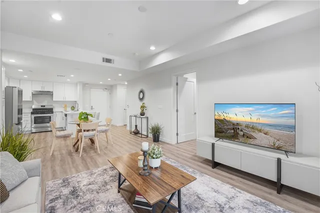 a living room with furniture kitchen view and a wooden floor