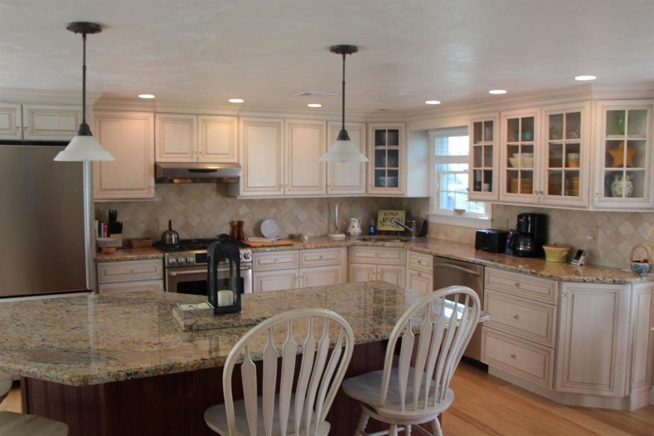 206 Clipper Road Bourne, MA 02532 - Photo 22 of 35 a kitchen with stainless steel appliances granite countertop a stove top oven a sink a dining table and chairs with wooden floor