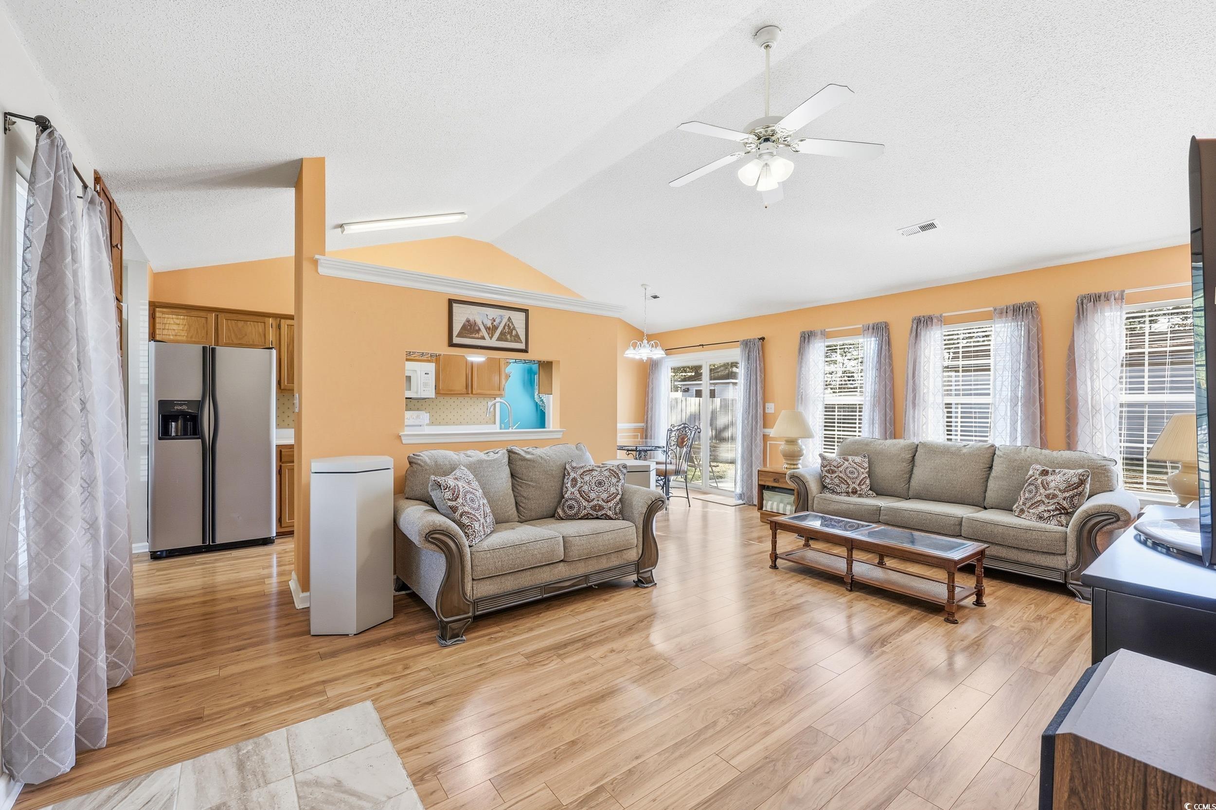 2560 Wild Game Trail Myrtle Beach, SC 29588 - Photo 5 of 24 Living room featuring light wood finished floors, vaulted ceiling, a textured ceiling, a chandelier, and a ceiling fan