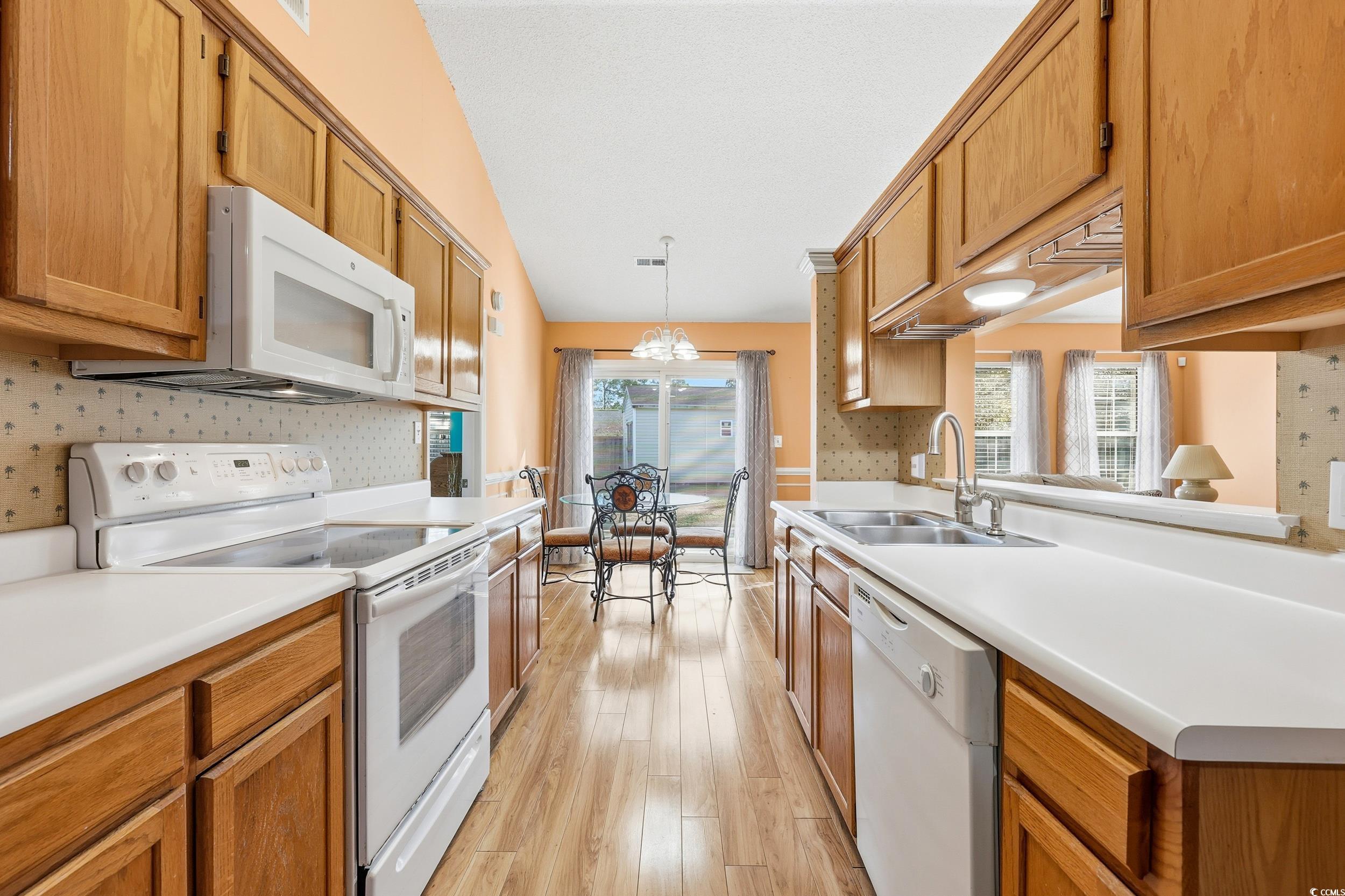 2560 Wild Game Trail Myrtle Beach, SC 29588 - Photo 6 of 24 Kitchen with white appliances, light countertops, pendant lighting, and brown cabinetry