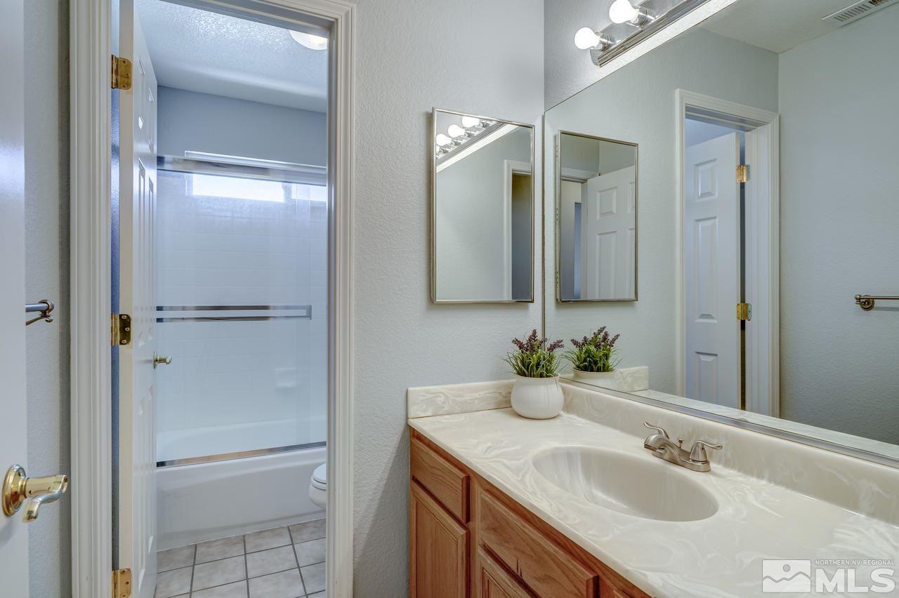 14435 Ghost Rider Drive Reno, NV 89511 - Photo 25 of 30 a bathroom with a granite countertop sink and a mirror