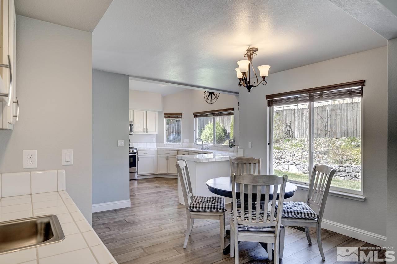 14435 Ghost Rider Drive Reno, NV 89511 - Photo 9 of 30 a dining room with wooden floor a chandelier fan a wooden table and chairs