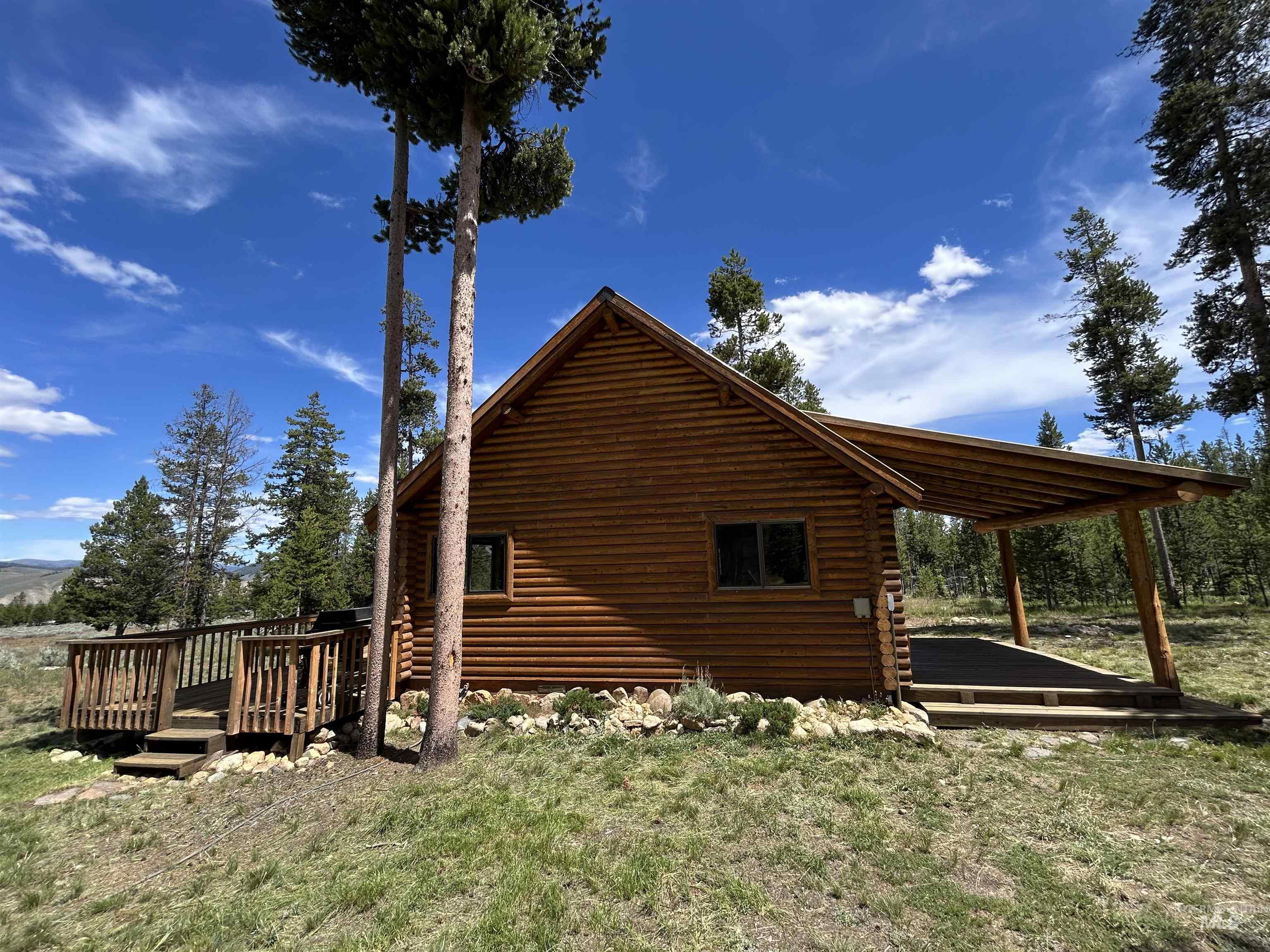 35 Sawtooth Way Stanley, ID 83278 - Photo 8 of 36 Log cabin exterior featuring a covered porch, a wooden deck with railing, and natural landscaping