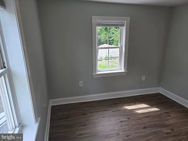 an empty room with wooden floor and window