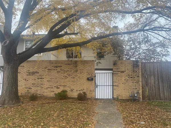 a view of a brick house that has tree in front of it