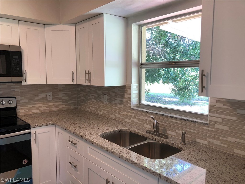 19 Connecticut Road Lehigh Acres, FL 33936 - Photo 3 of 26 a kitchen with granite countertop a sink and a window